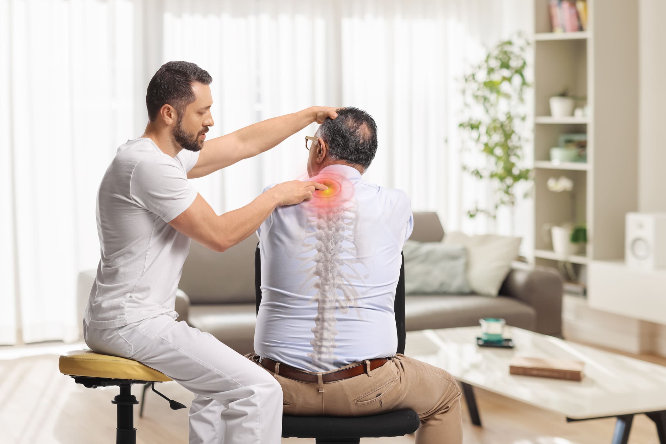 A physical therapist examines an older man's neck and upper back, with a digital overlay highlighting pain and the spine in a bright, modern room.